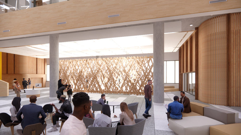 An open space with a feature wall. Groups of people are sitting at small tables and chairs, while a person holding a baby is walking in the background. To the right, two people are sitting and talking on couches.