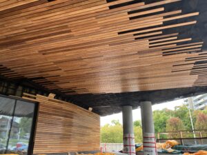 Image of the outside of Ādisōke, with the installation of the red cedar wood along the walls and ceiling, right next to the windows. 
