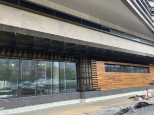 Image of the outside of Ādisōke, with the installation of the red cedar wood and stonework along the walls, right next to the windows. 
